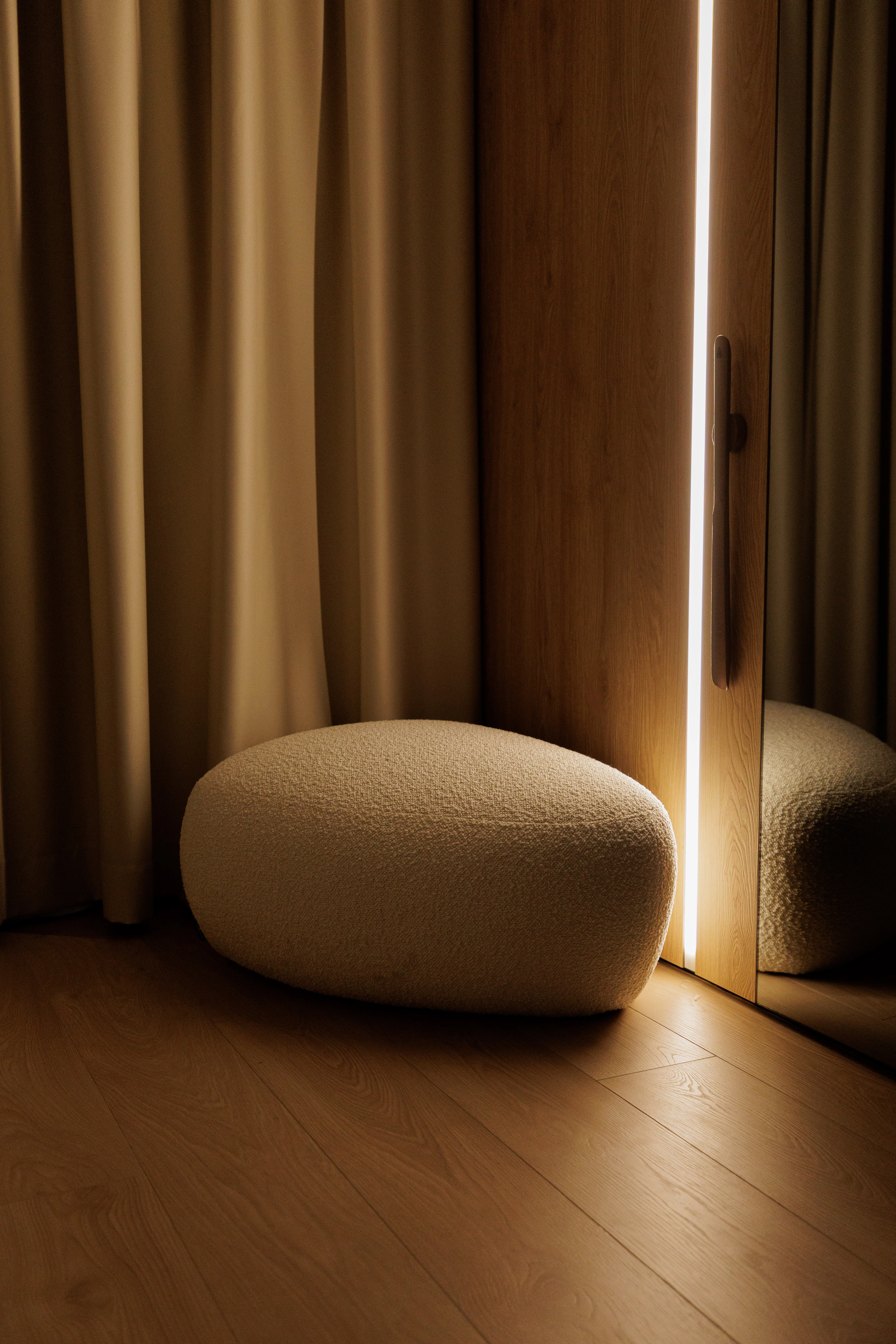 Three Chios poufs in cream, grey and ivory fabrics on a polished cement studio floor with pampas grass behind