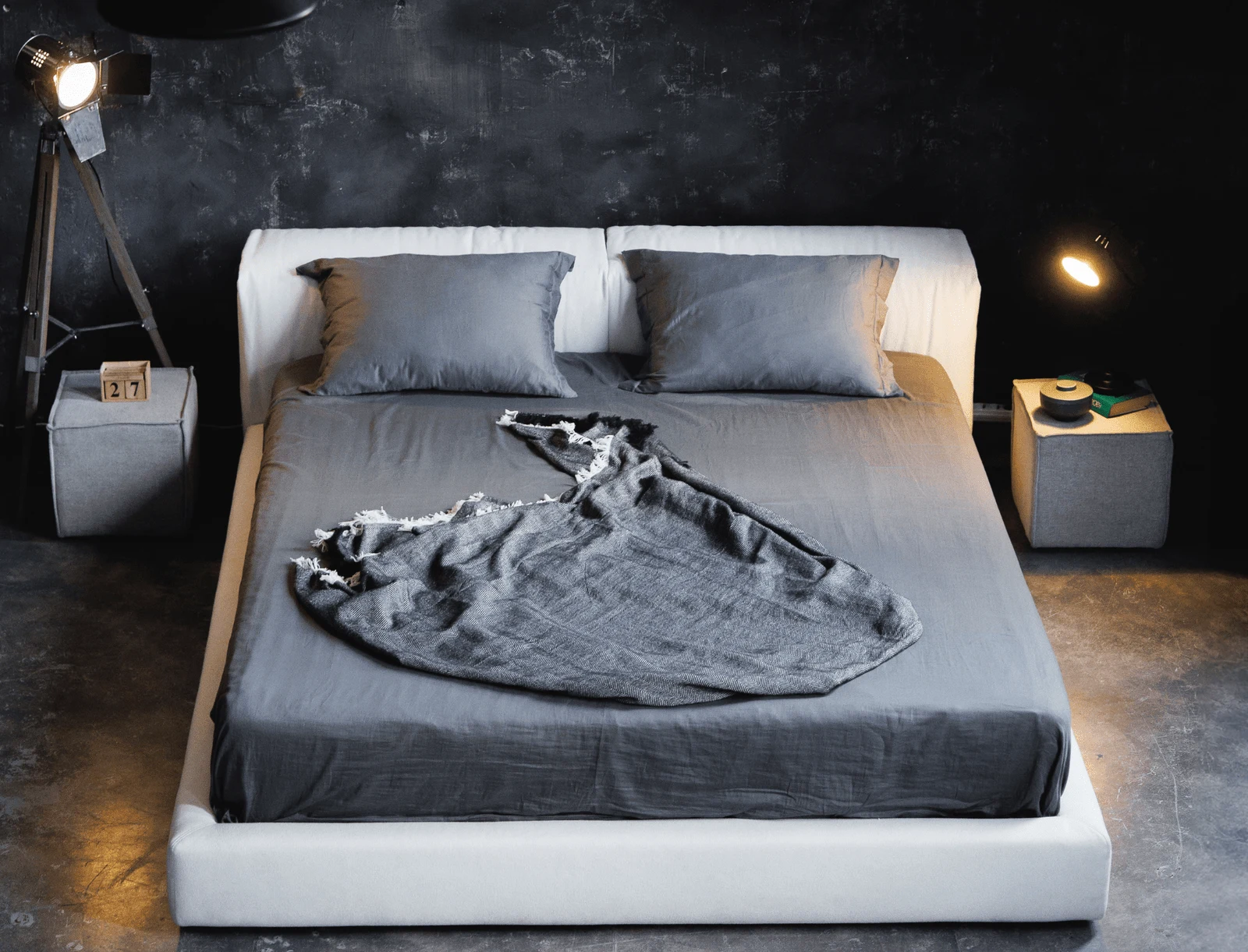 Cream Soho 900 Marmaris in a dark concrete-walled loft with a grey duvet and a photographic light stand on the right