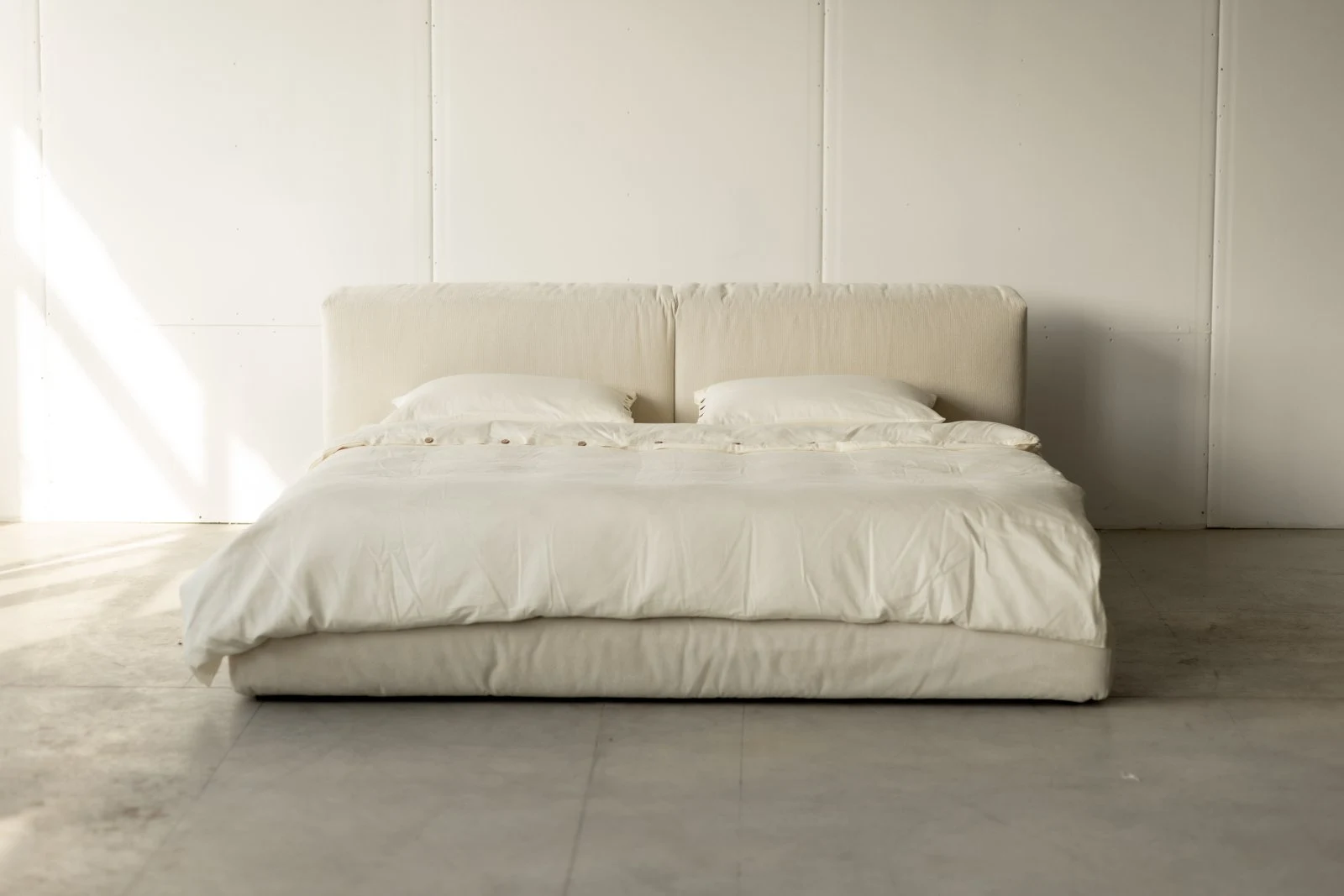 Cream Marseille 901 Marmaris in a bright minimal studio with white panel walls, button-row bedding draped across the bed