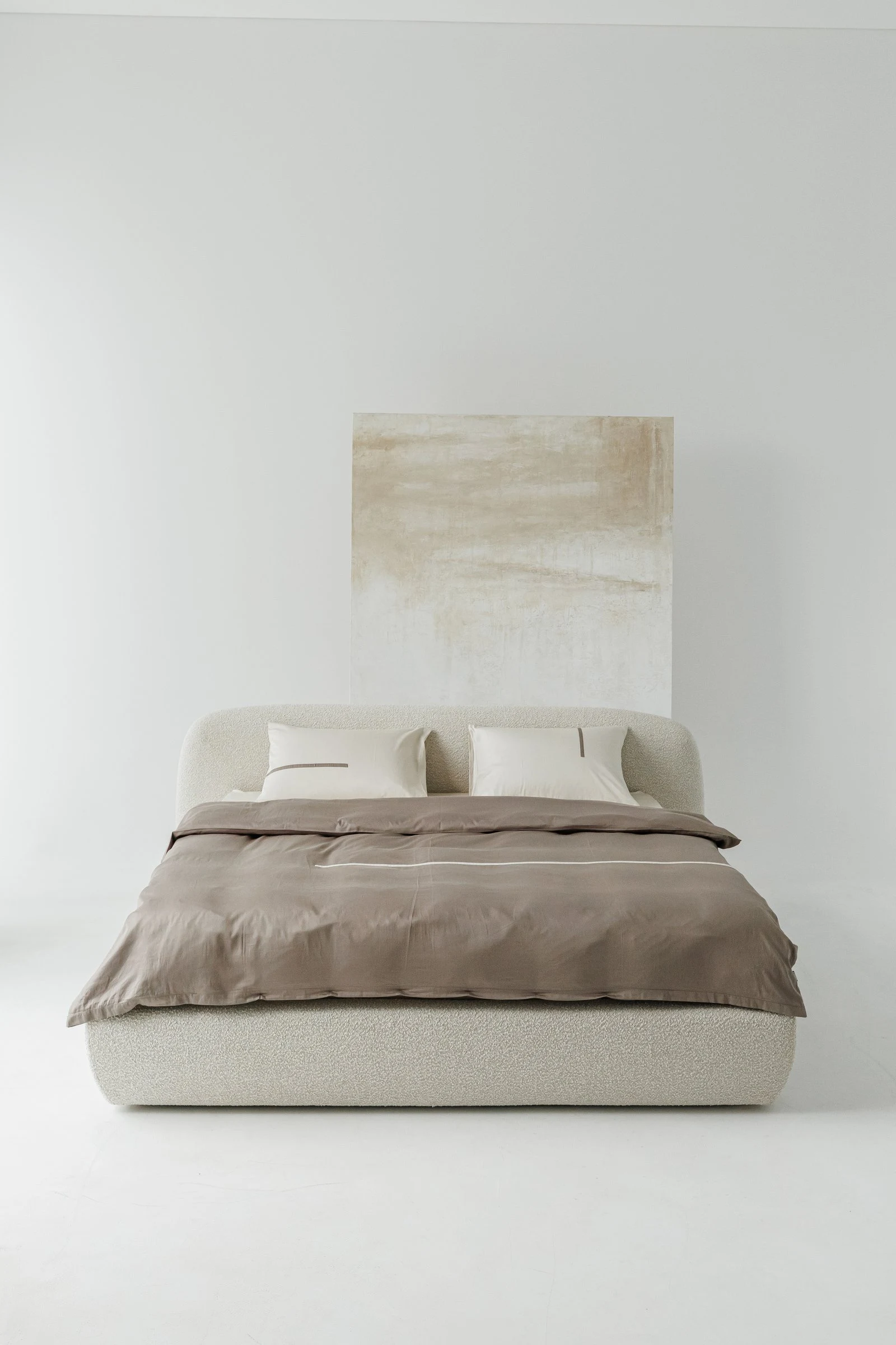 Cream boucle Belagio in a white studio with a textured painted canvas leaned against the wall as a backdrop