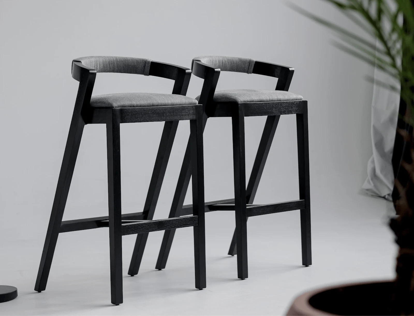 Two Baffi bar stools photographed in a clean studio on white floor with a soft plant nearby