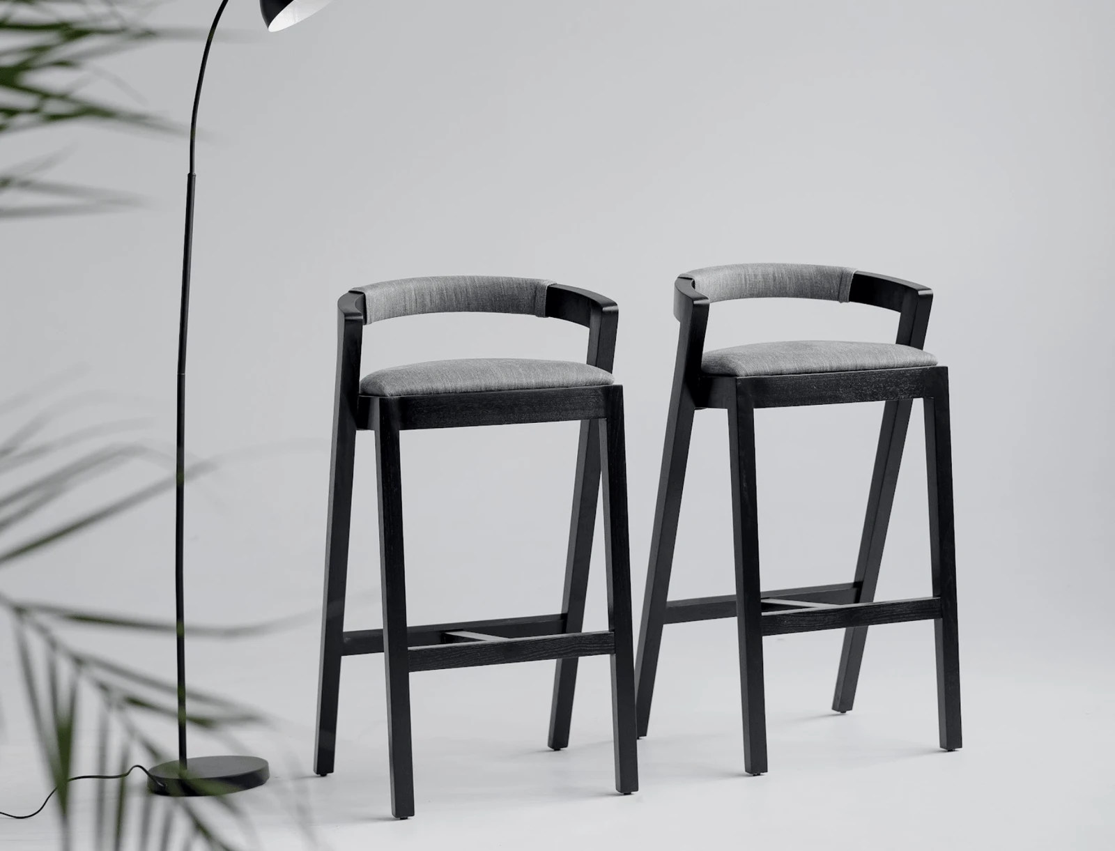 Baffi bar stools in a clean studio with a black floor lamp beside them