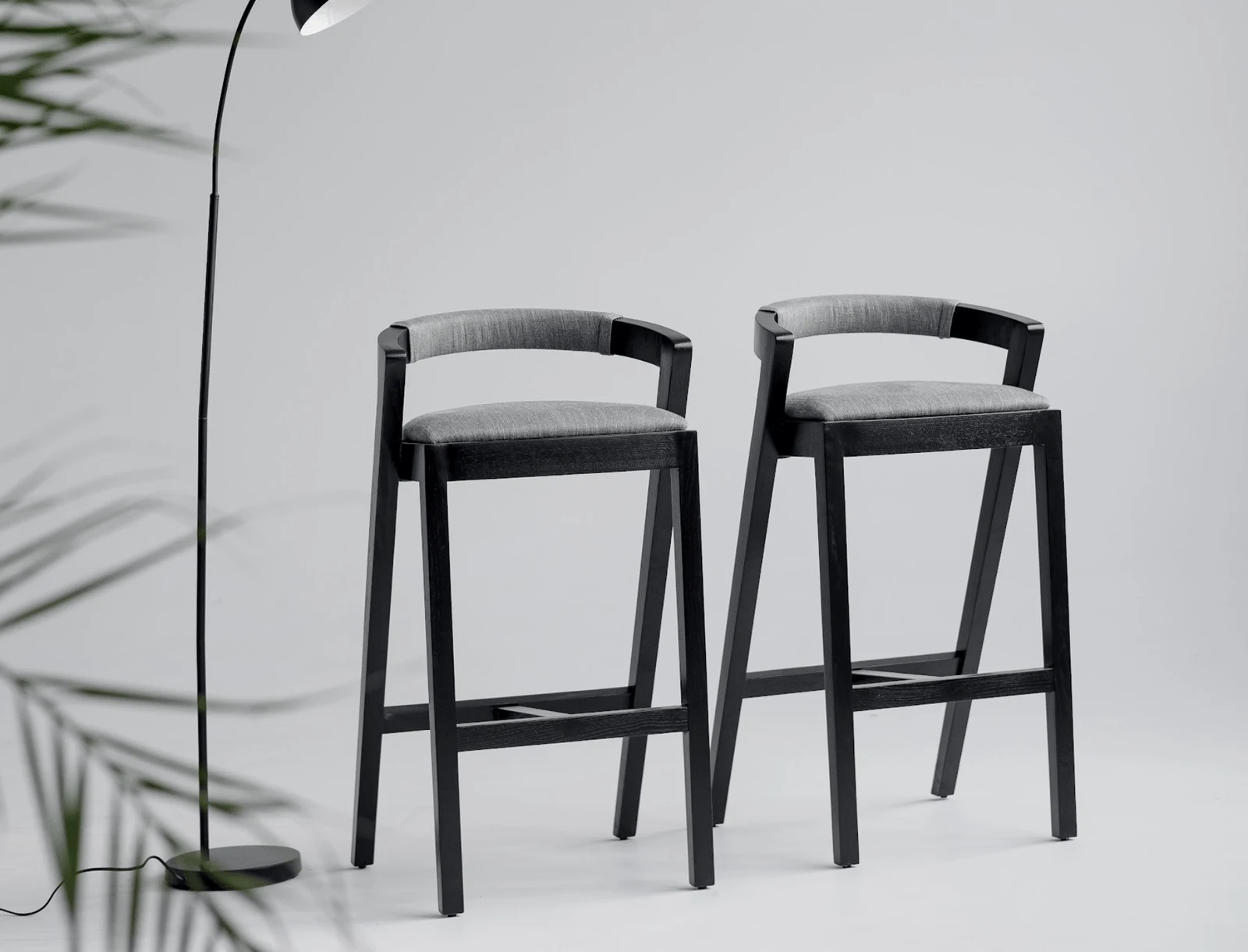 Baffi bar stools in a clean studio with a black floor lamp beside them