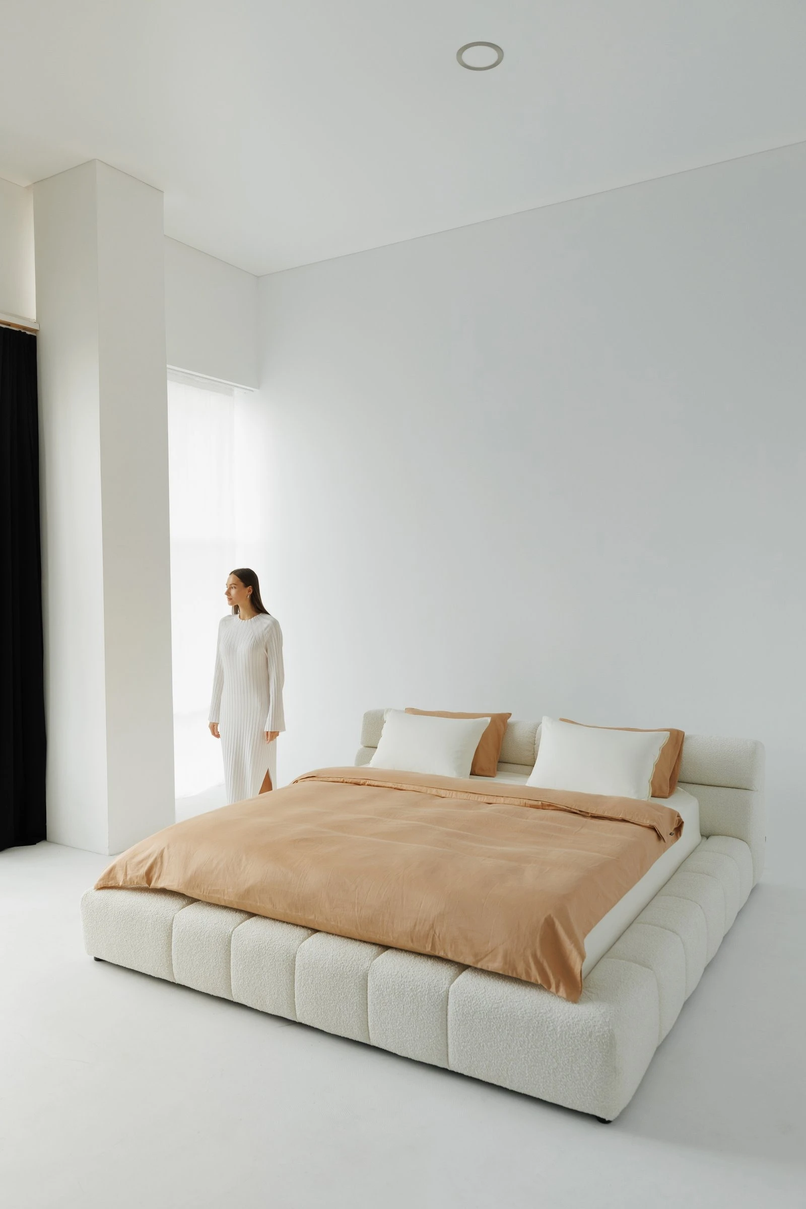 Cream boucle Nao in a bright white room with a model in white ribbed loungewear standing nearby