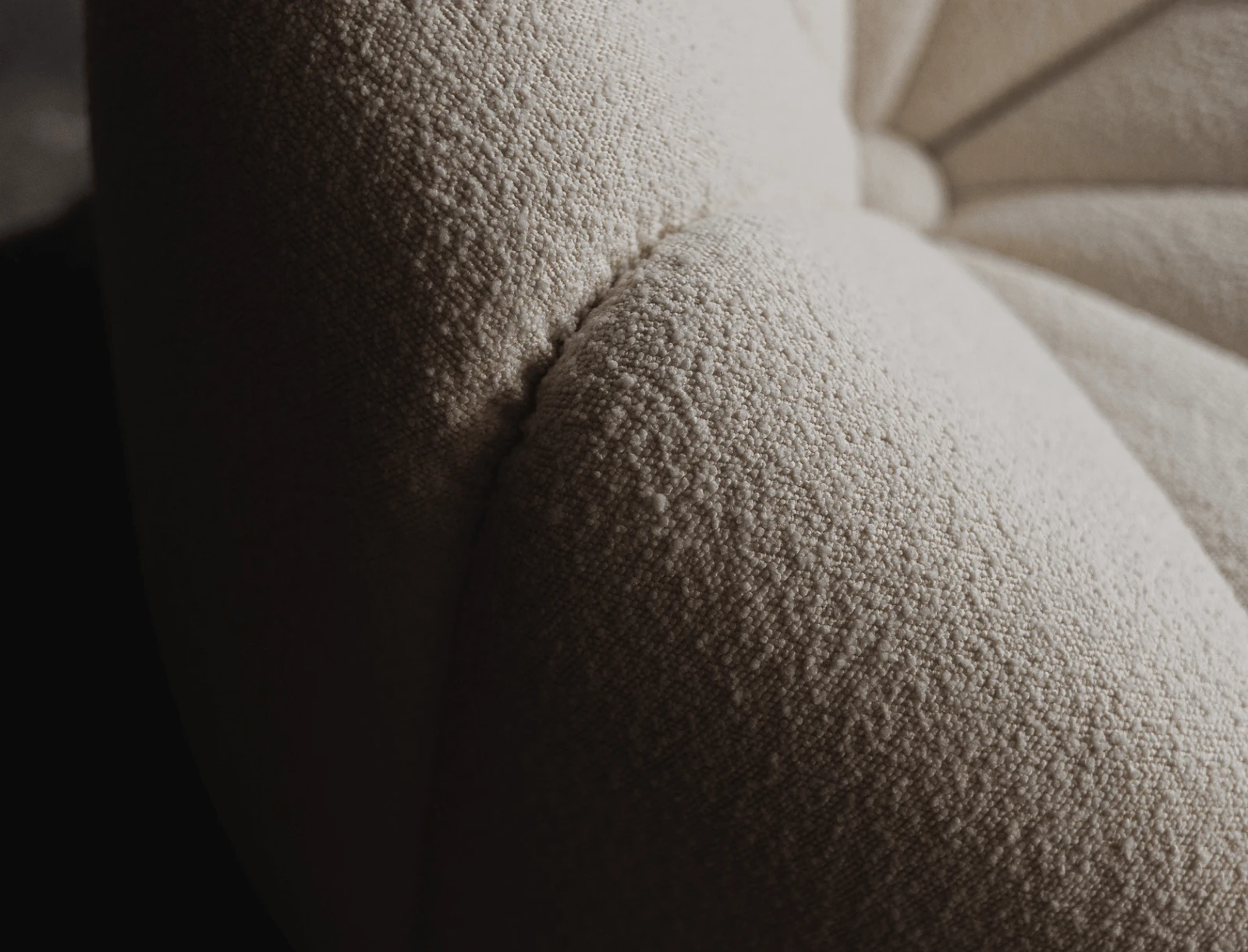Three-quarter detail of the cream Flora chair indoors against a dark wall