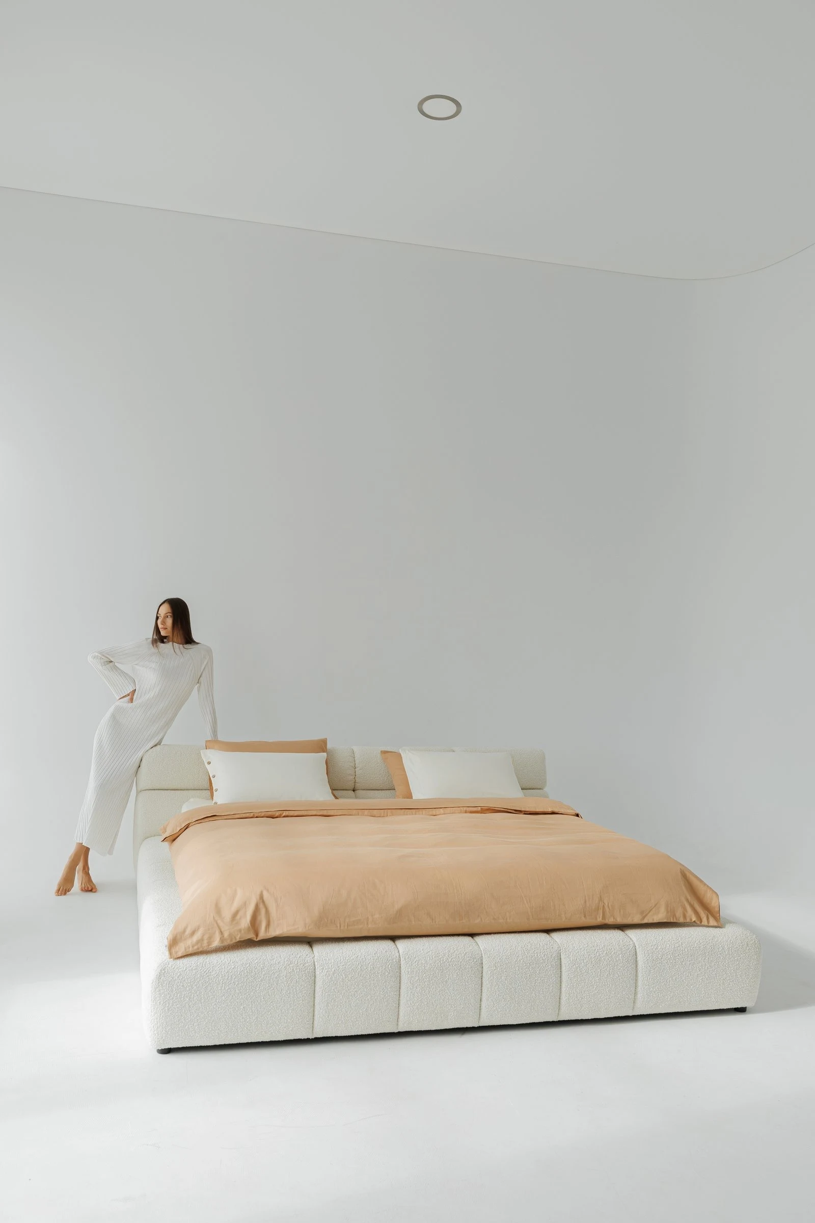 Cream boucle Nao with a model leaning into the headboard pillow