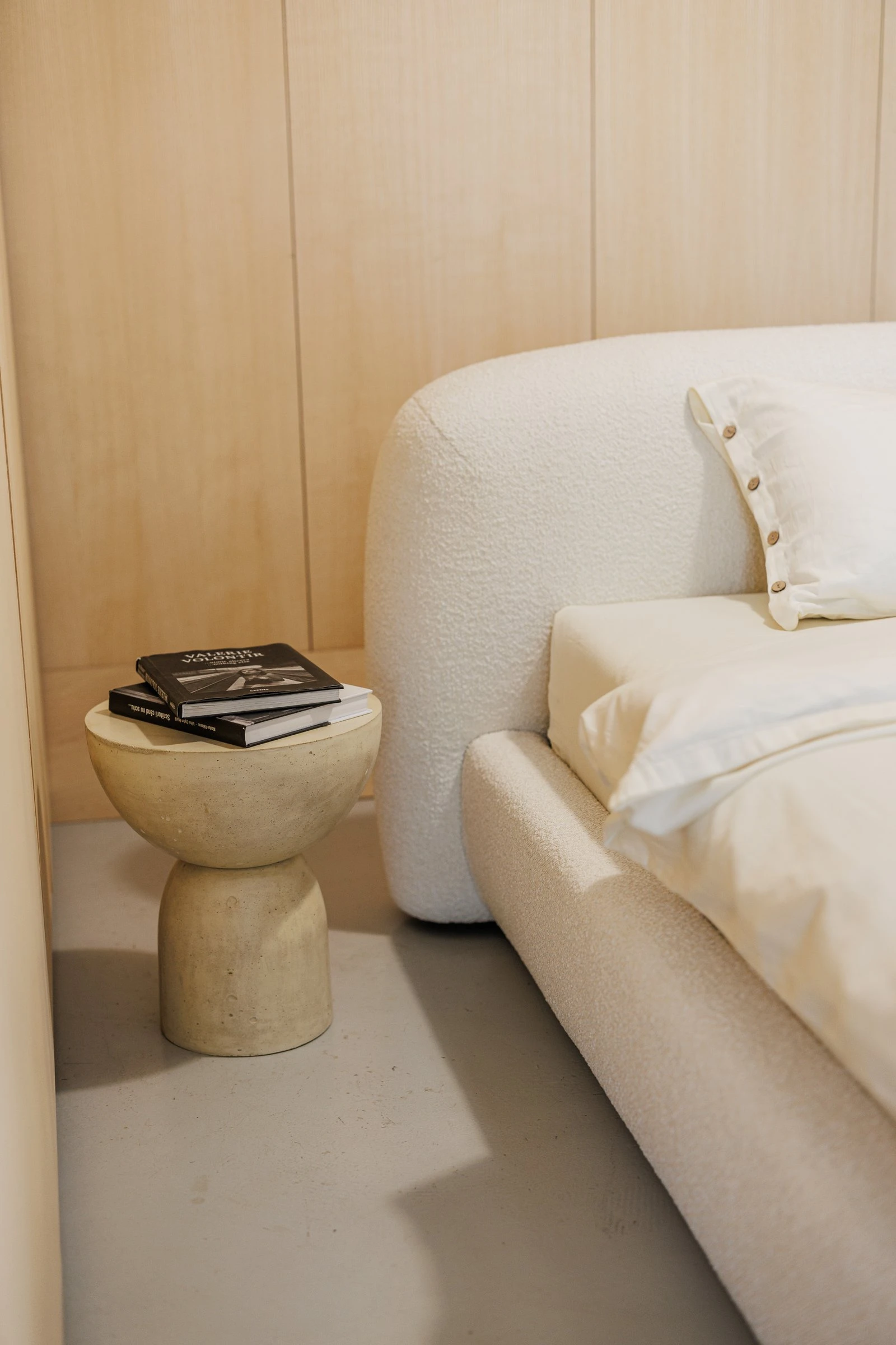 Stone side table beside the Belagio holding two black design monographs, cream boucle in the frame