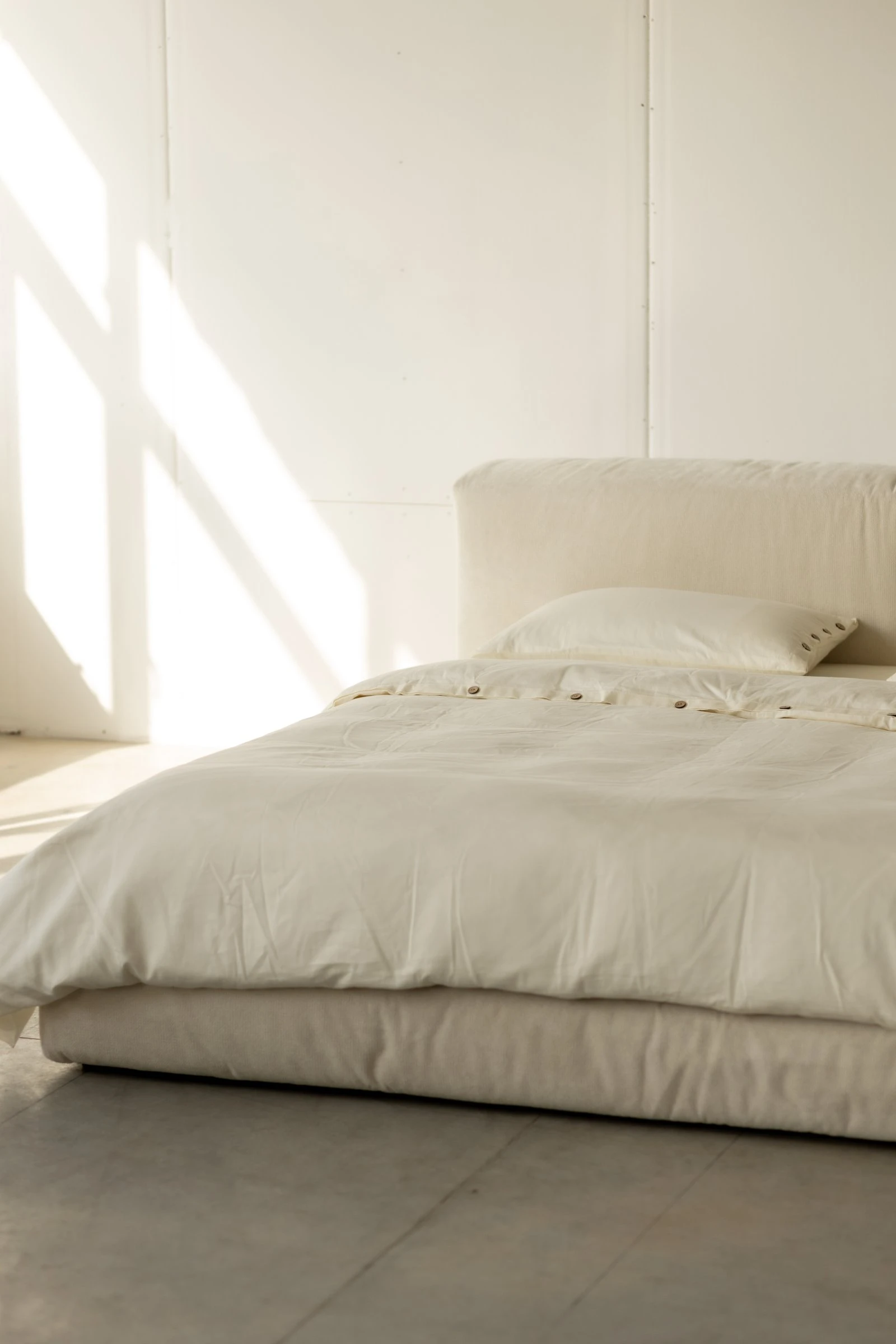 Side view of the Marmaris with white bedding draping off the edge in a clean studio