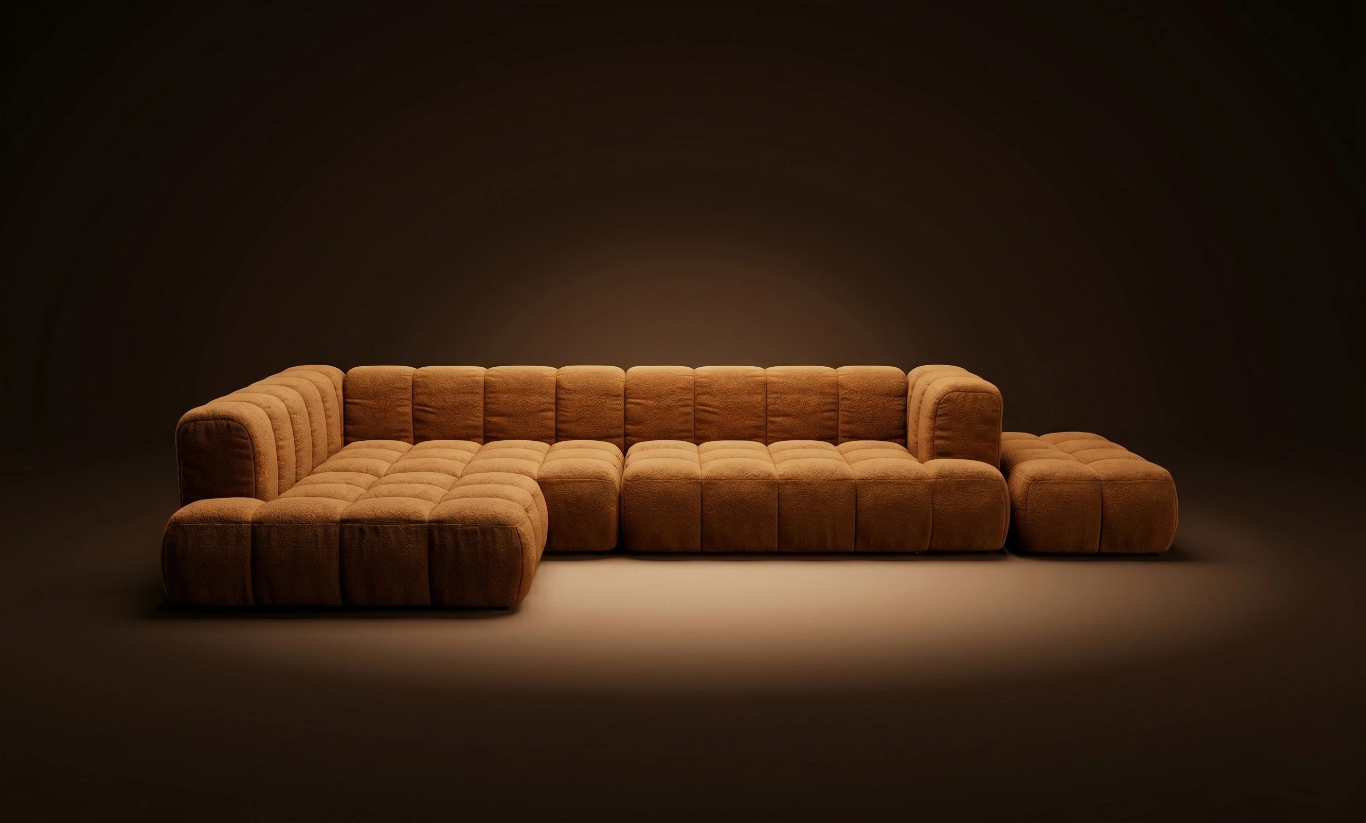 A cognac Mille three-seater with attached ottoman, in a dark studio