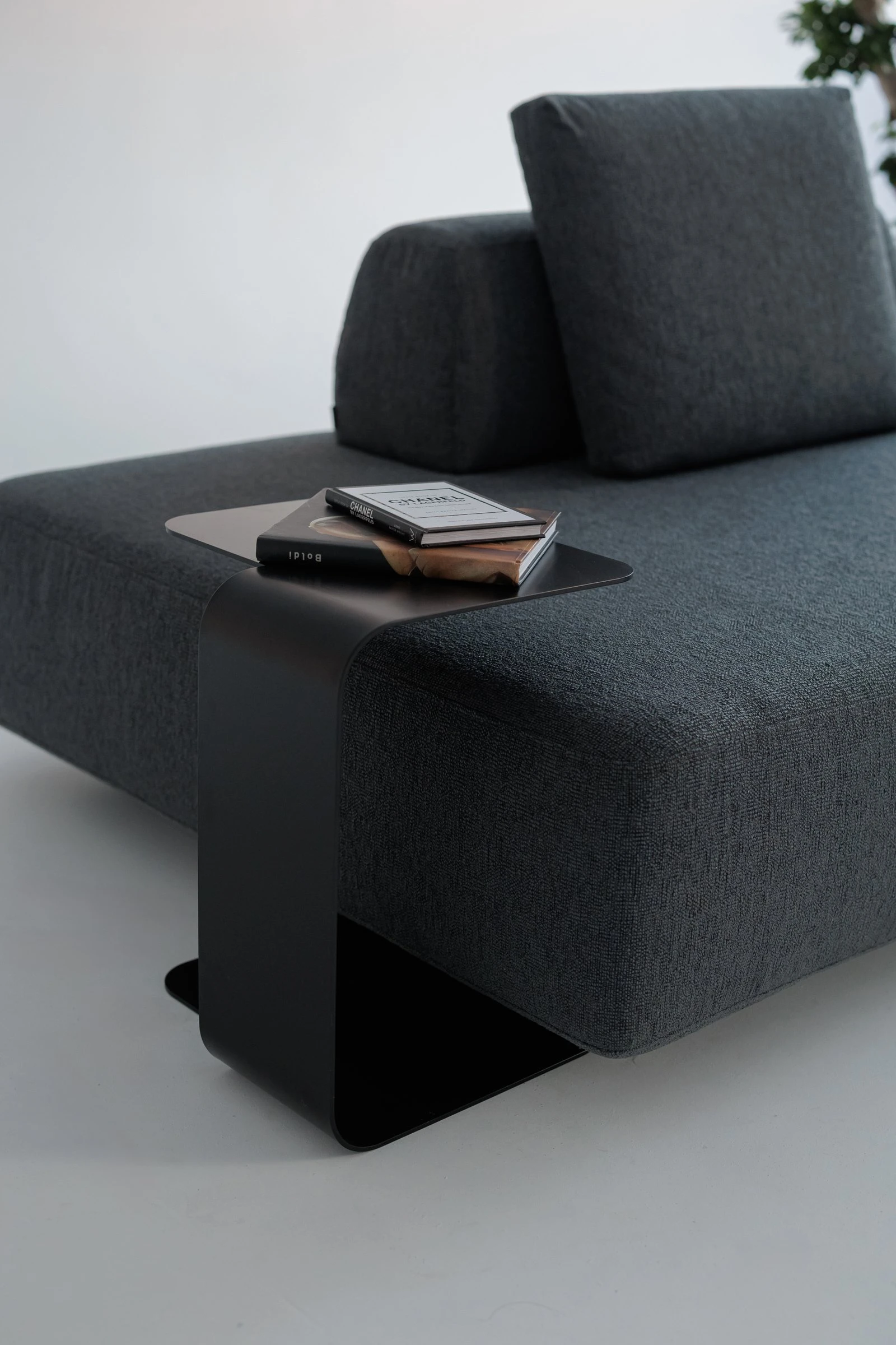Close detail of the charcoal Deseda with a black metal side table holding a Chanel book