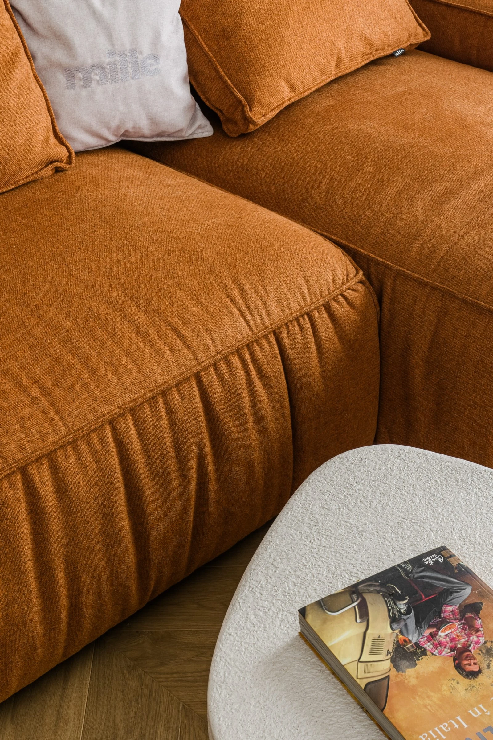 Close detail of the cognac Milano with a Mille pillow and an Italian magazine on a small boucle table
