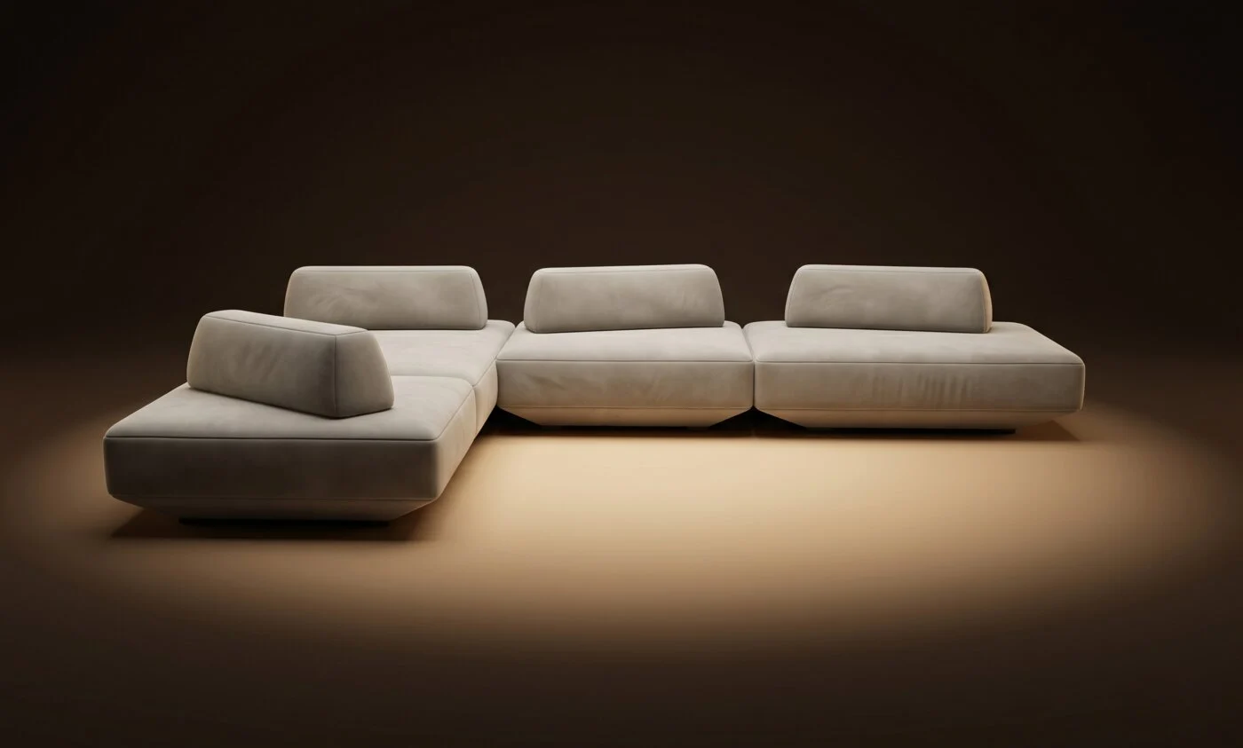 Cream Deseda four-module L-shape with multiple bolsters on a warm-dark spotlit stage