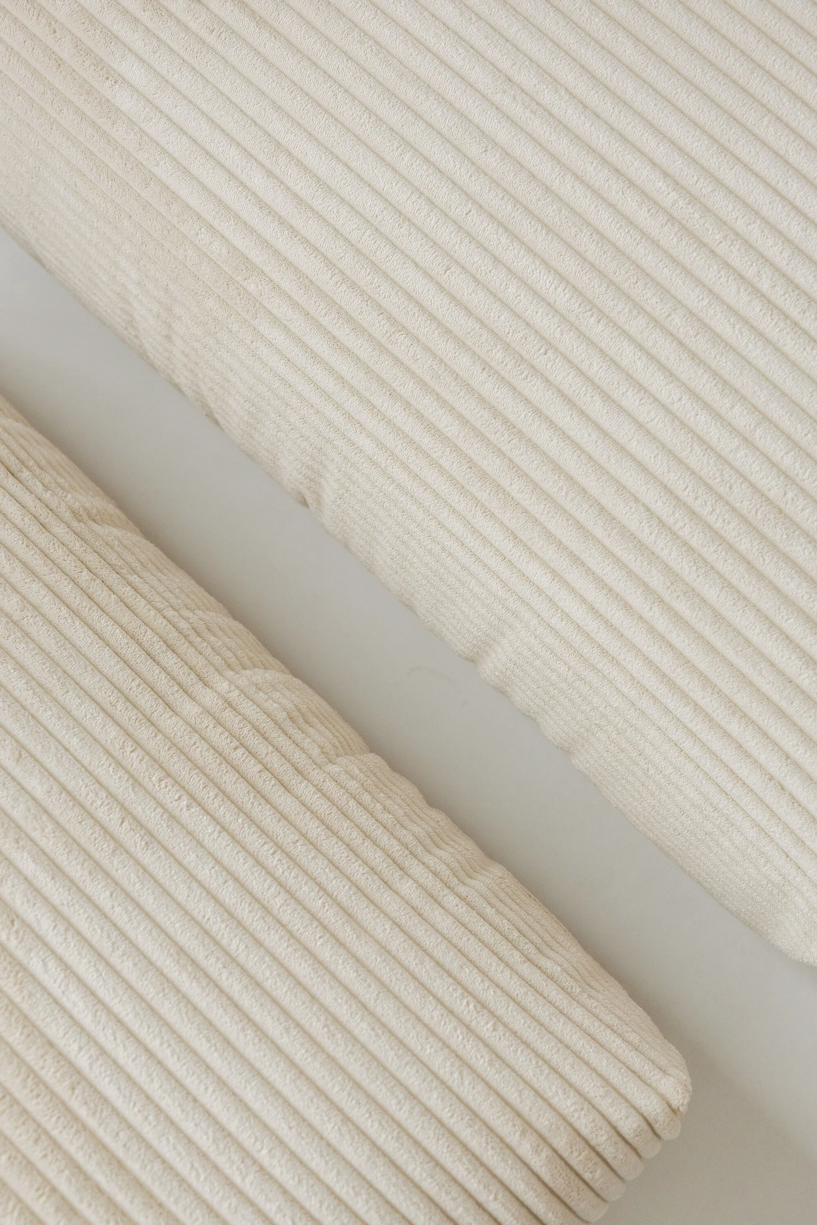 Macro detail of two oat corduroy Tesa cushions with wide diagonal ribbing