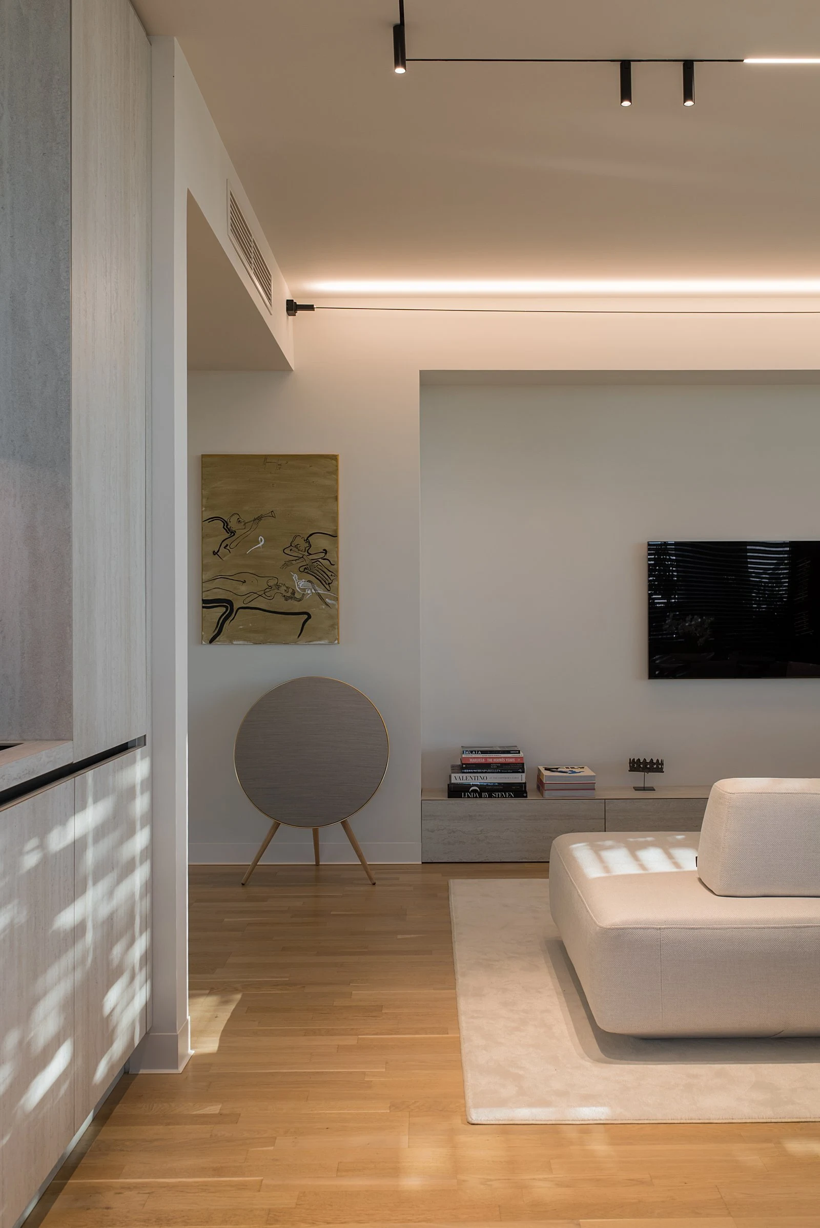 Cream Deseda corner with a piece of artwork on the wall and a brass speaker stand