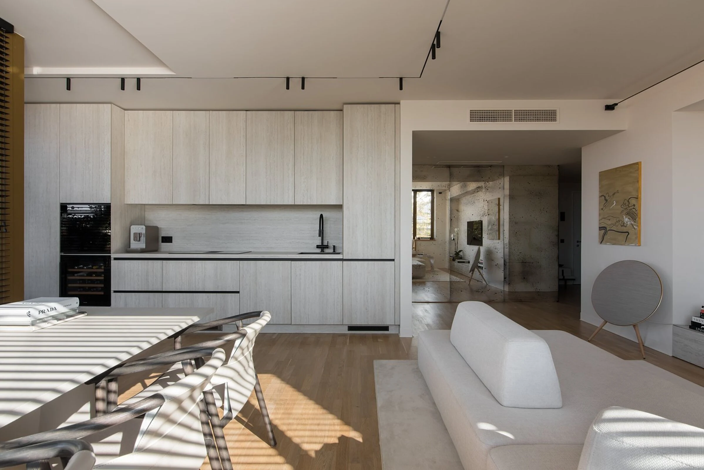 Cream Deseda viewed from across a real apartment kitchen with white cabinetry, a mirrored panel, and floor-to-ceiling windows behind