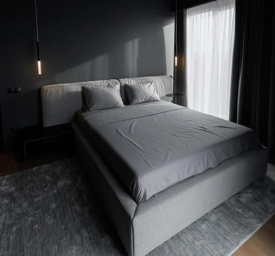 Mid-grey Palermo in a dark-walled bedroom with hanging tube pendants and a sheer curtain at the window