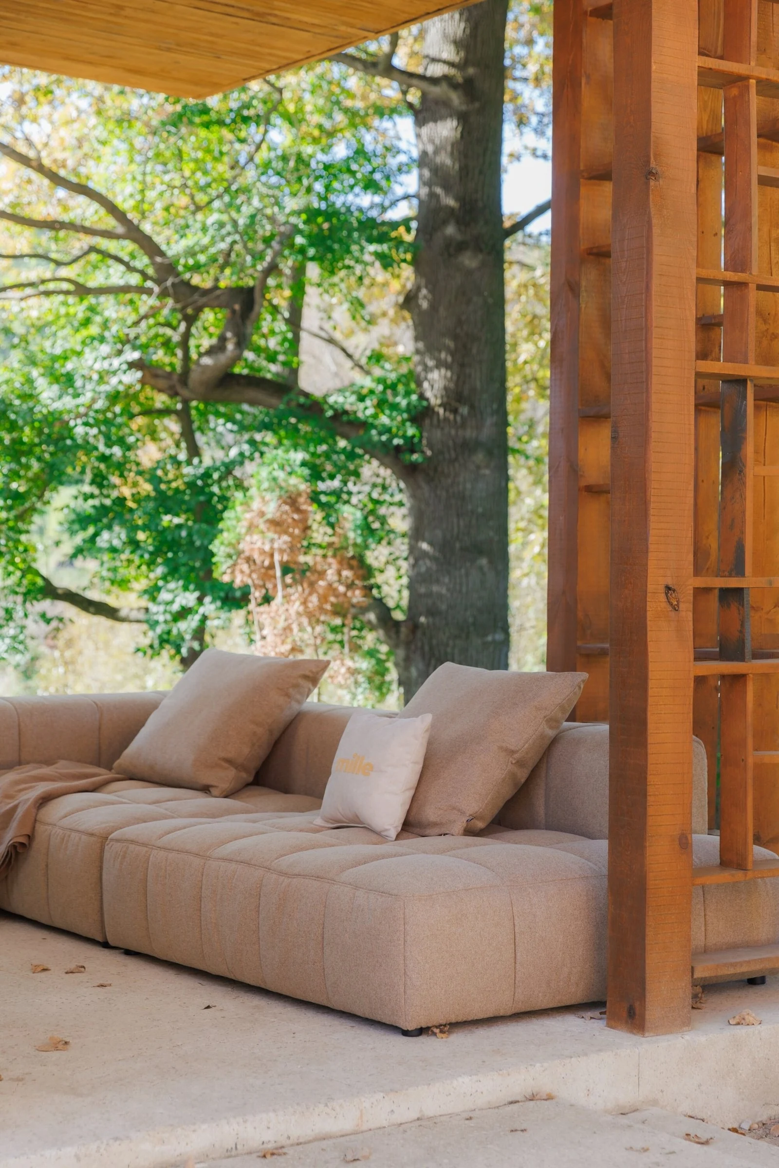 Tan Soft on a stone-and-wood terrace with a wooden lattice column and mountain trees