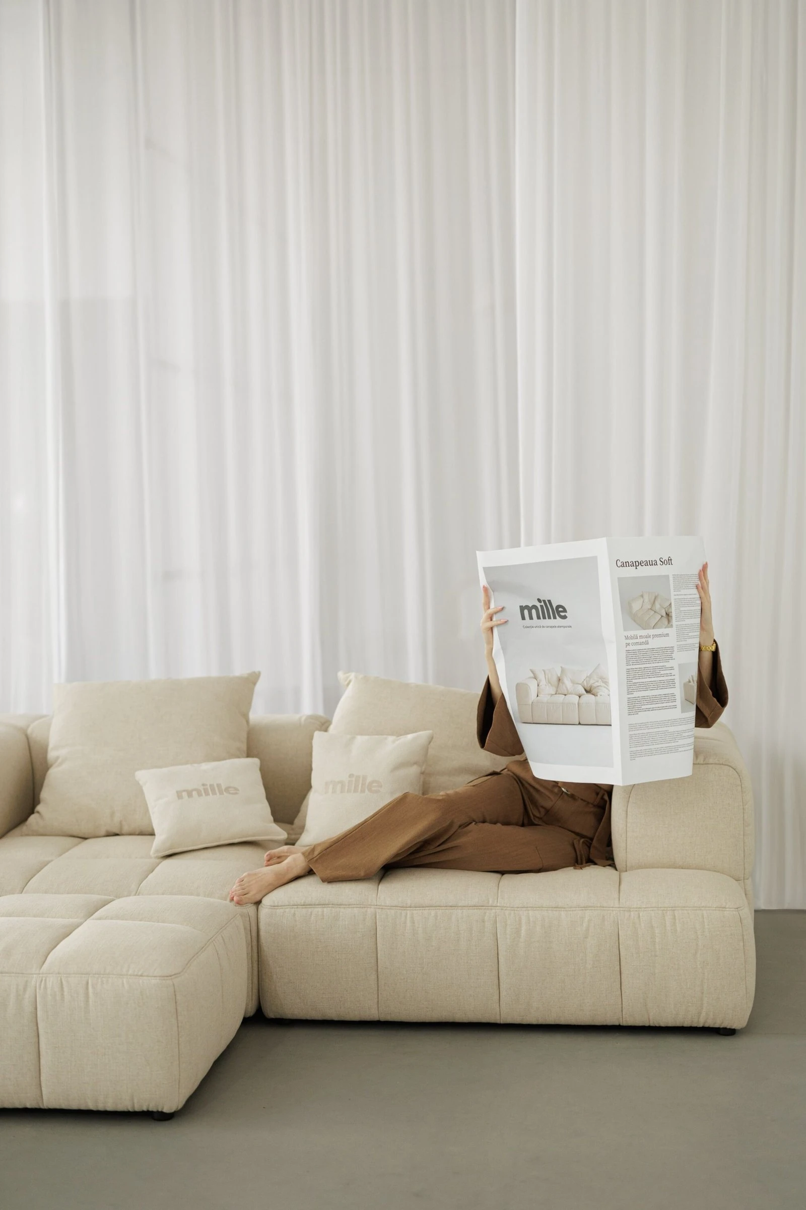Close detail of a Mille pillow held against the cream Soft, model in camel beside