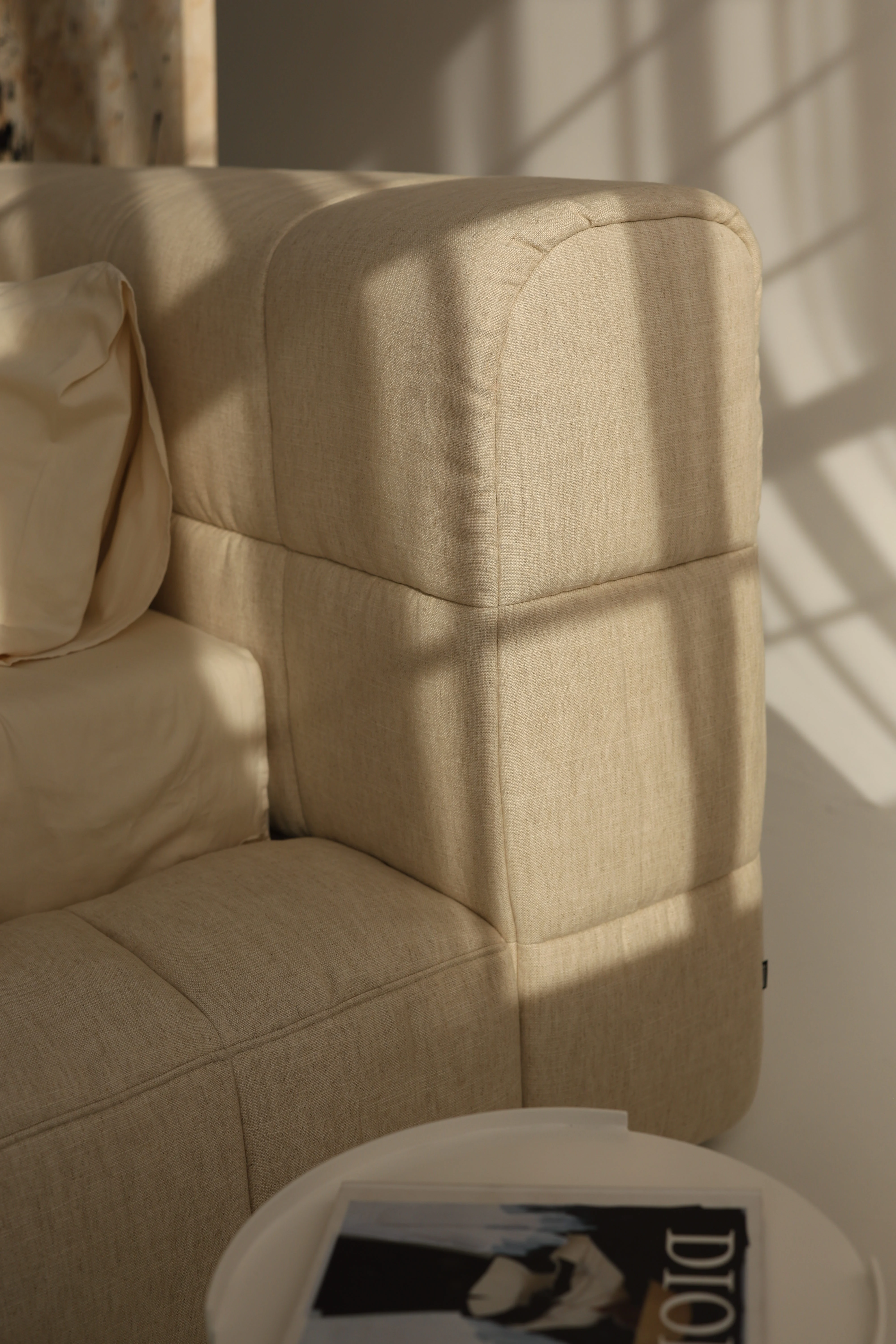 Close detail of the Nao headboard with hard window-light raking across the channelled seams