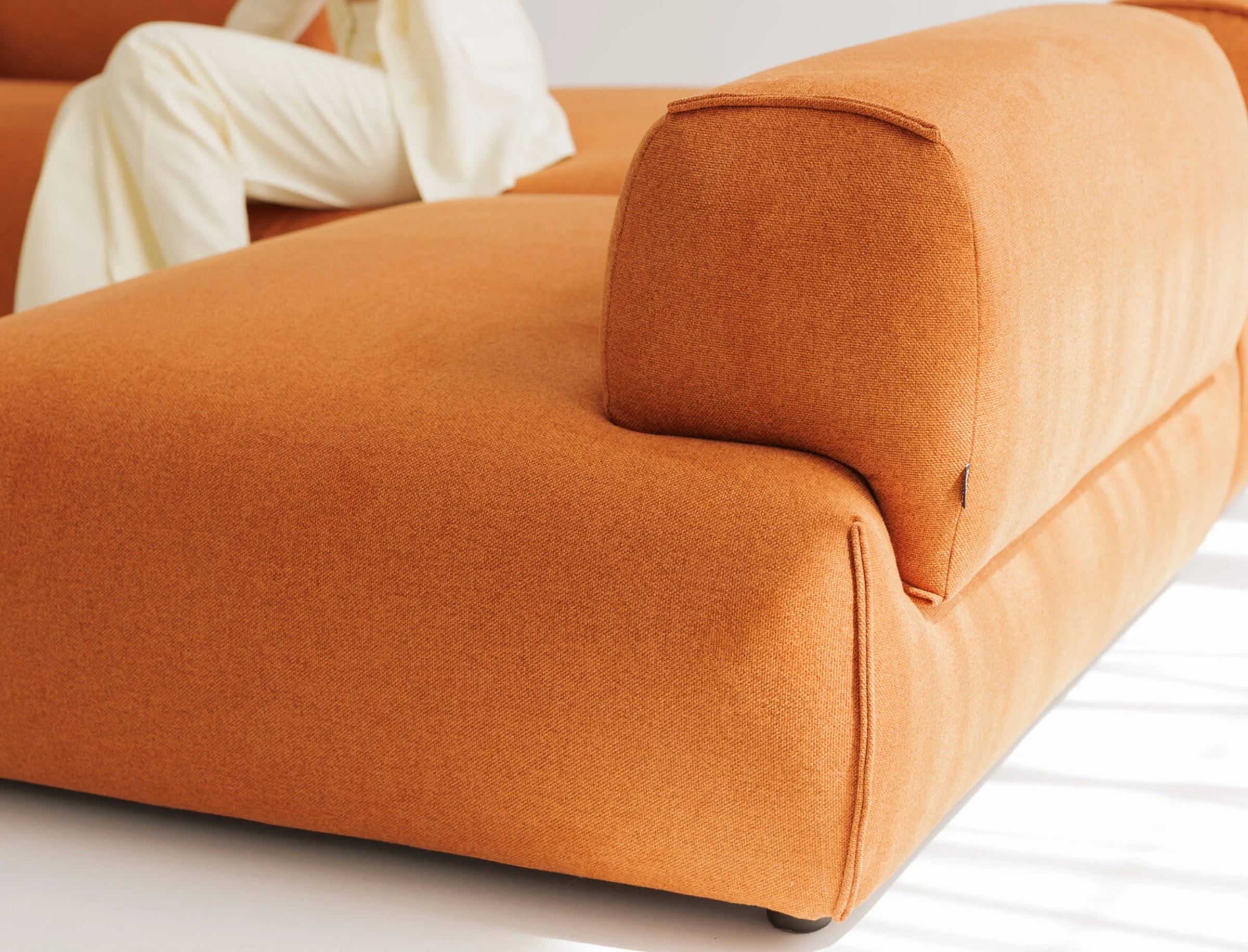 The Nissa modular sofa in rust upholstery, in a studio with an abstract art panel, a short editorial loop