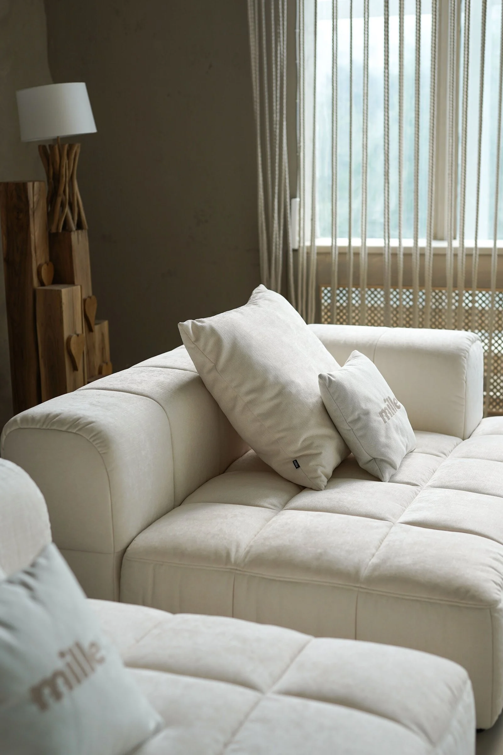 Cream tufted Soft modular sofa in a Mediterranean villa with a sheer rope curtain and golden sun-stripes on the cushions