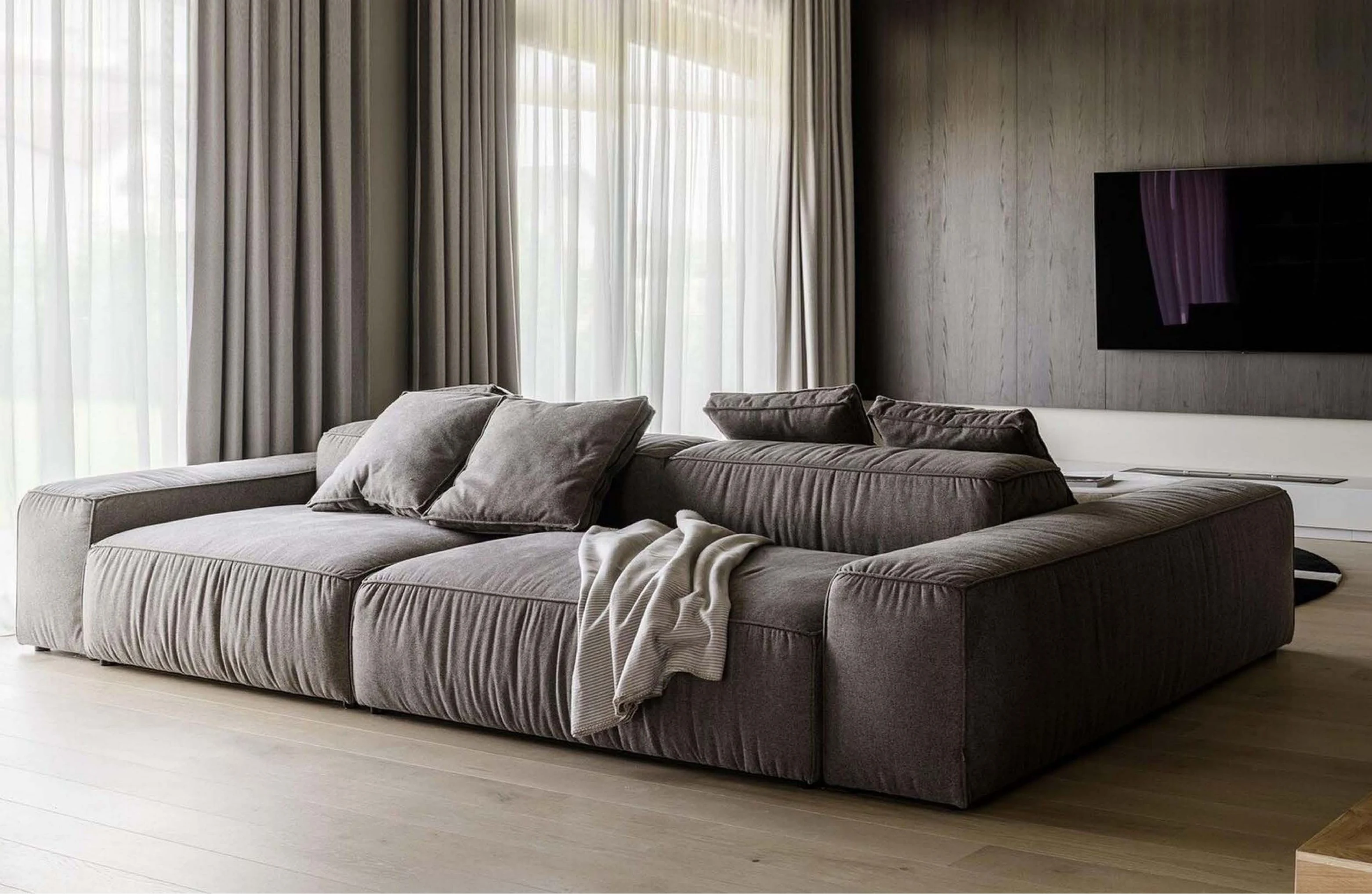 A cream L-sectional in a contemporary Riyadh apartment, dining nook behind.