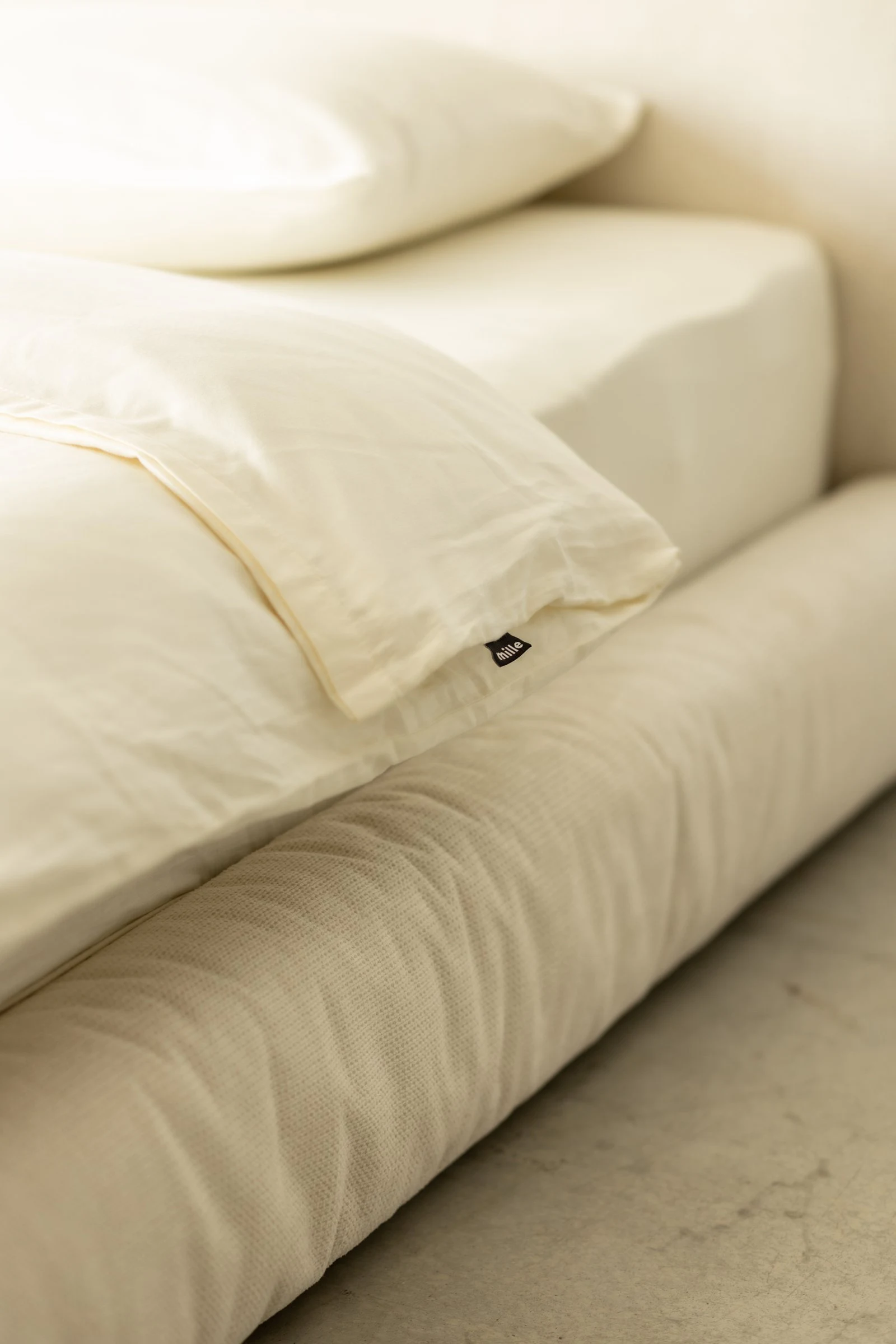 Macro of the small black Mille label sewn into the seam of the cream Marmaris pillow