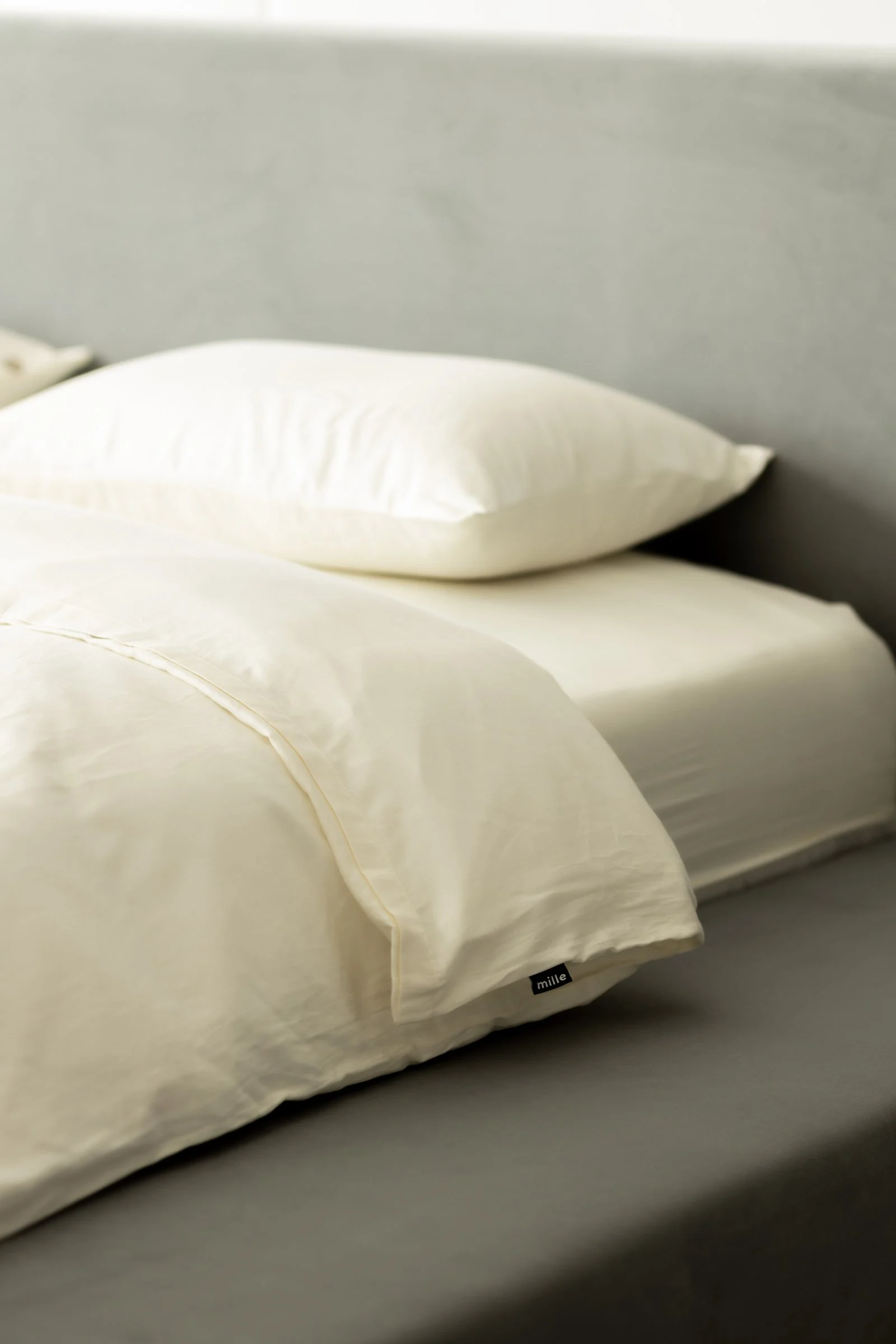 Close detail of the small Mille label sewn into the seam of the grey velvet Connect pillow