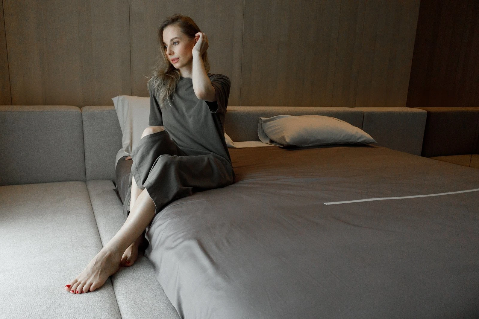 A woman in a dark linen outfit sitting on the side bench of a sand Connect bed