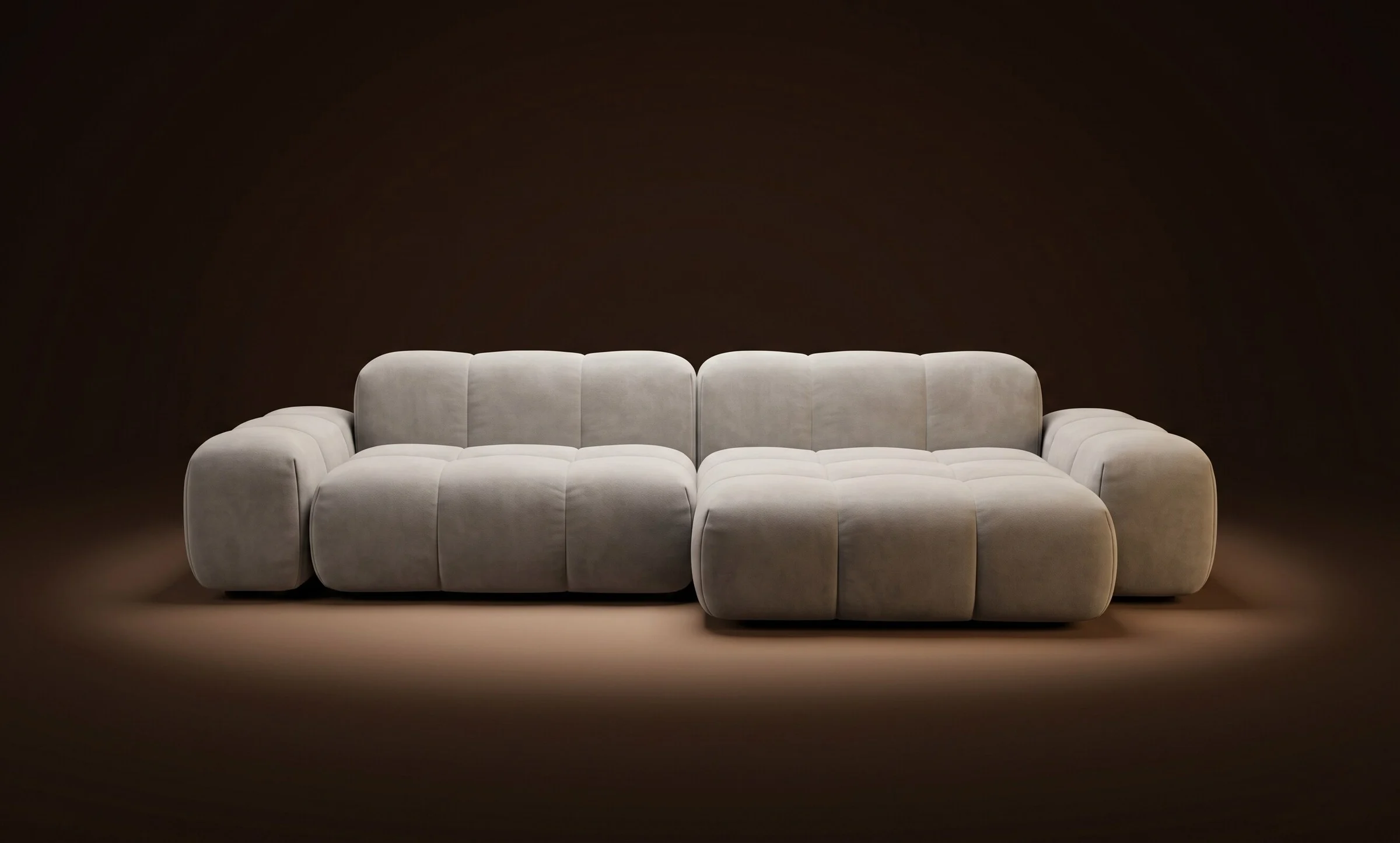 Cream Nami in an open L configuration with a chaise on a dark spotlit stage