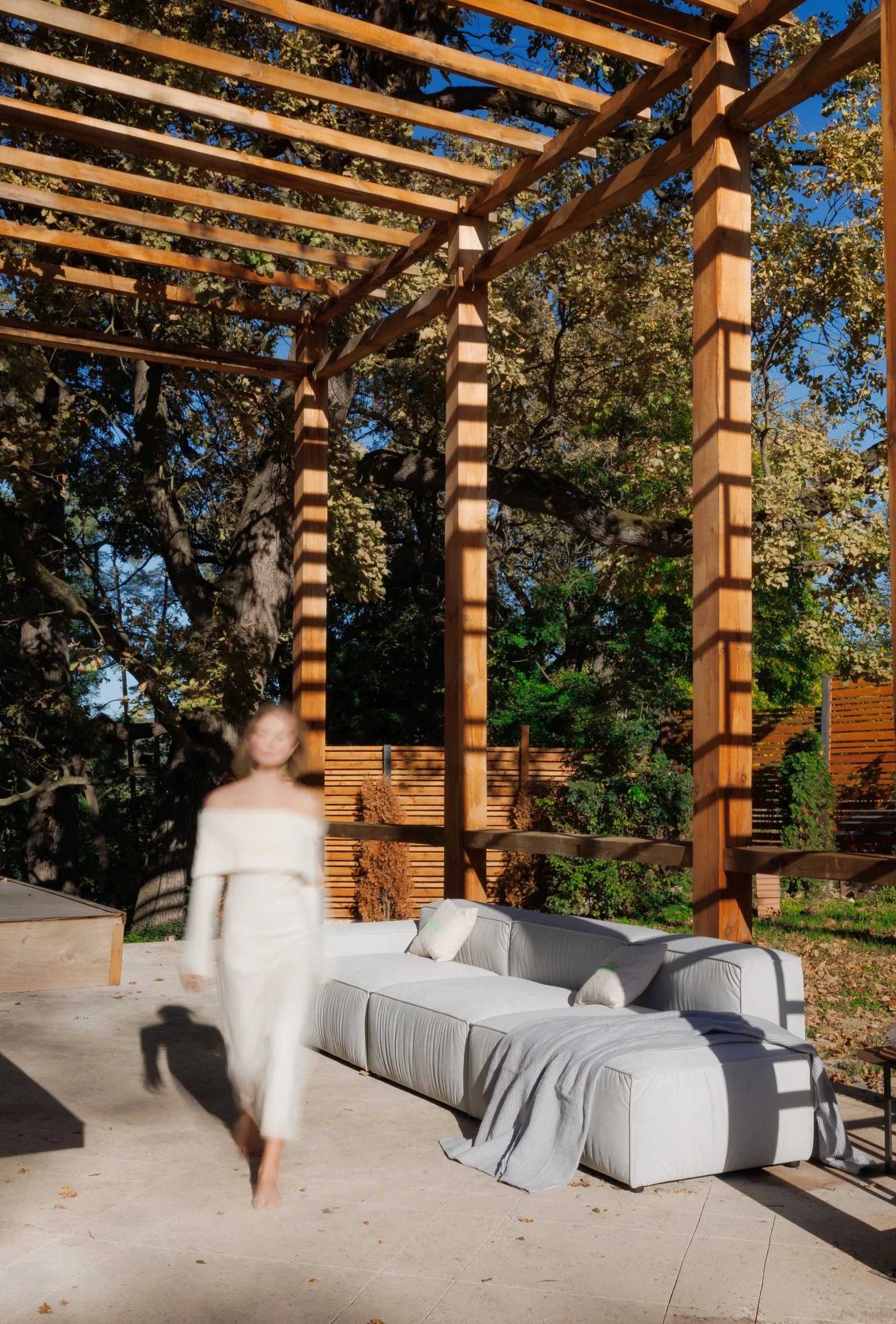 Cream outdoor Milano under a wooden pergola in late afternoon light