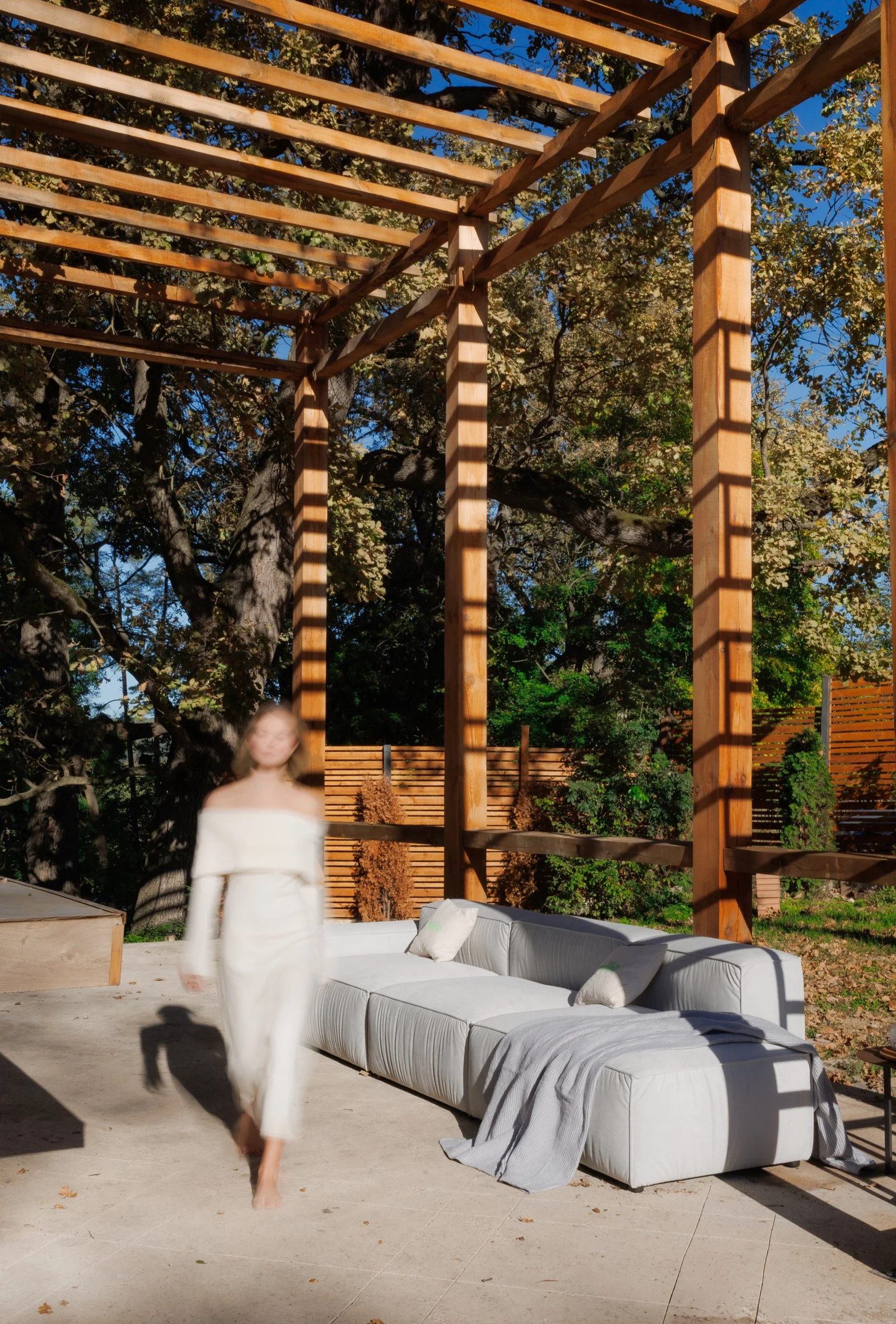 Cream outdoor Milano under a wooden pergola in late afternoon light