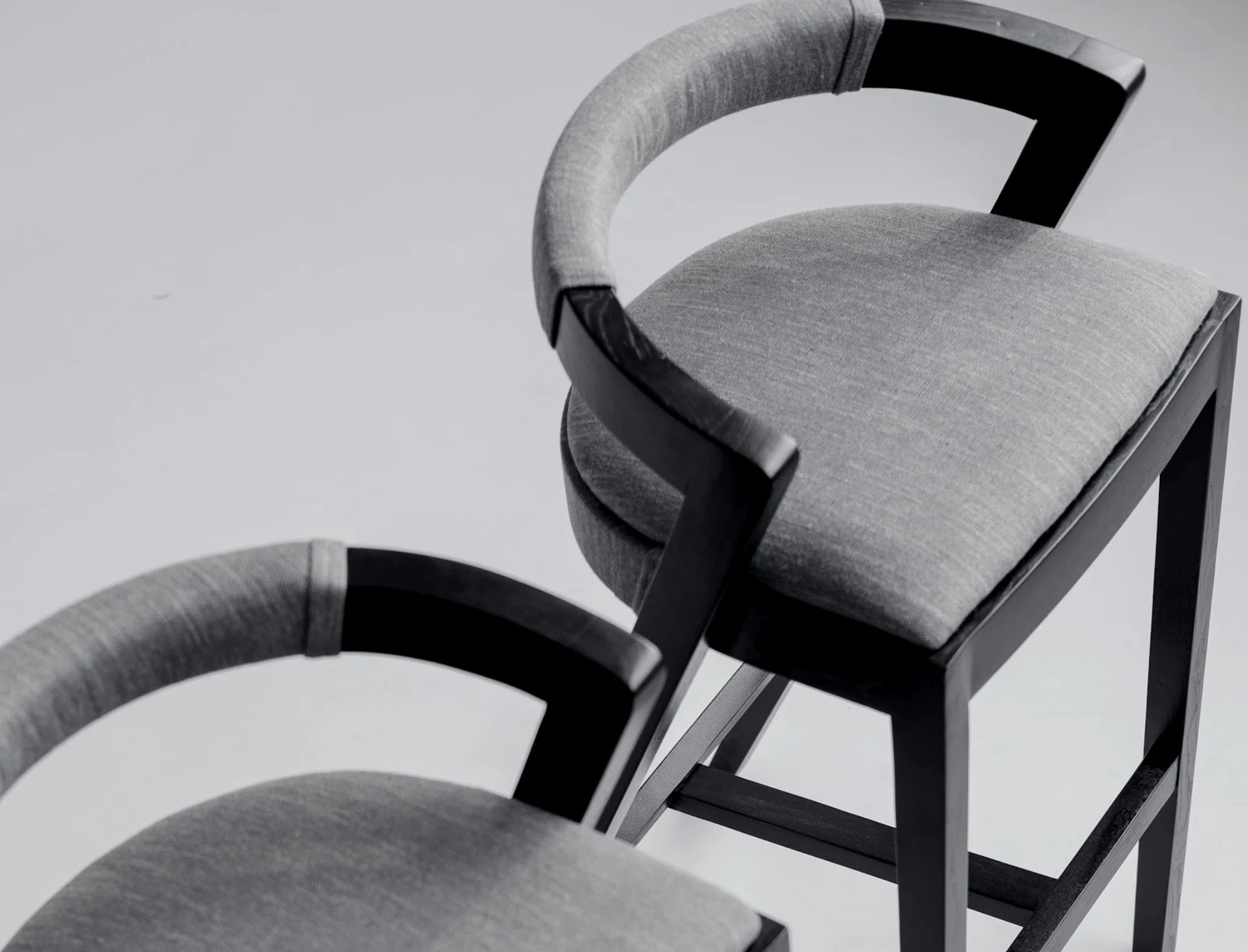 Three-quarter view of the Baffi bar stool showing the black-stained ash sawhorse frame and the round upholstered seat
