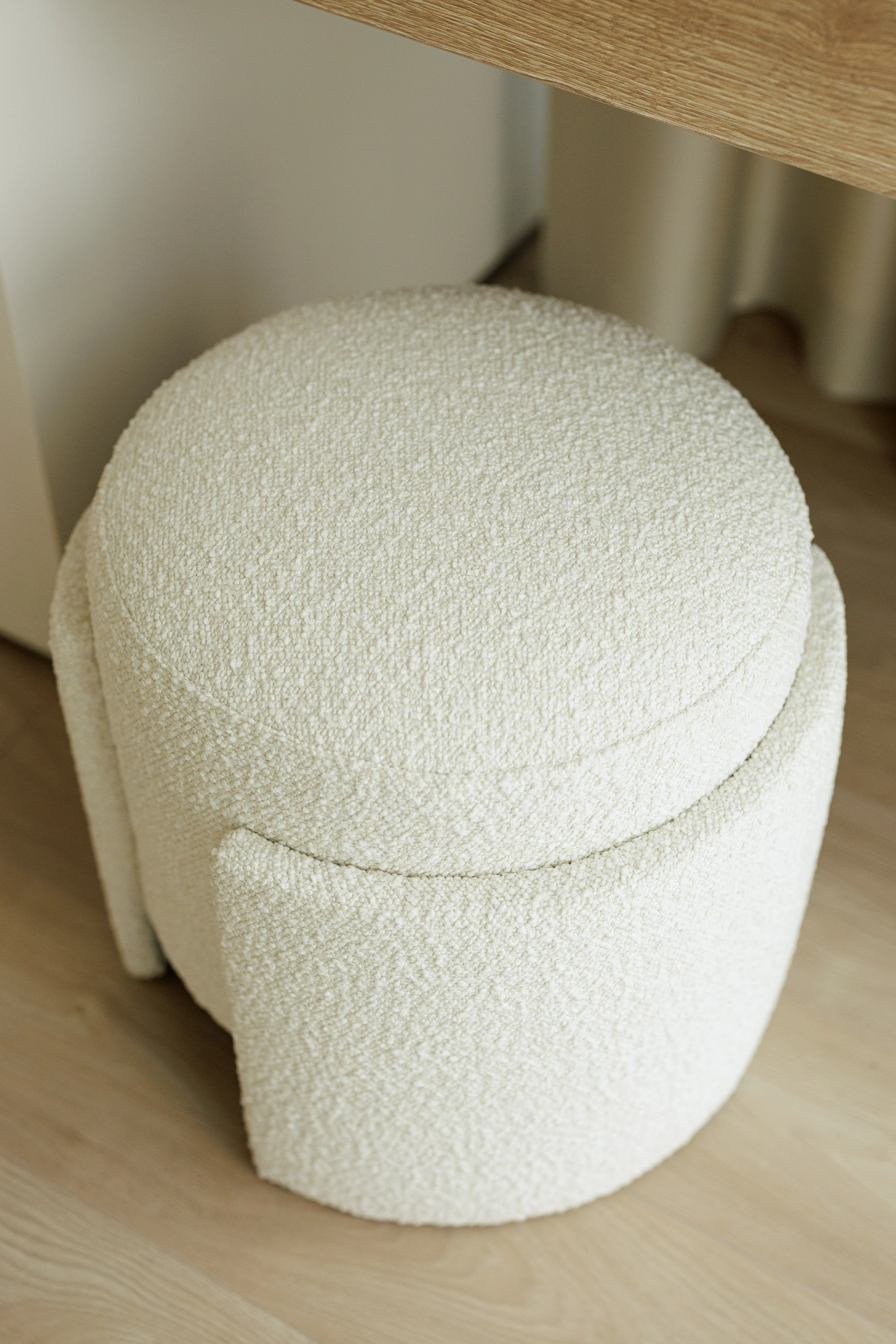 Studio render of cream boucle Eden pouf on herringbone parquet